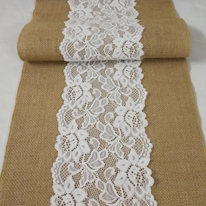 May include: A burlap table runner with a white lace trim. The lace has a floral pattern.