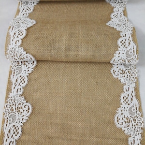 May include: A burlap table runner with white lace trim. The runner is folded in thirds, showing the lace trim on both sides.