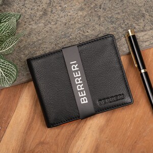 May include: A black leather wallet with a black and white label that says "BERRERI".