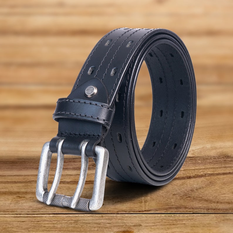 May include: A black leather belt with a silver double prong buckle. The belt has a stitched design and a row of holes for adjusting the size.