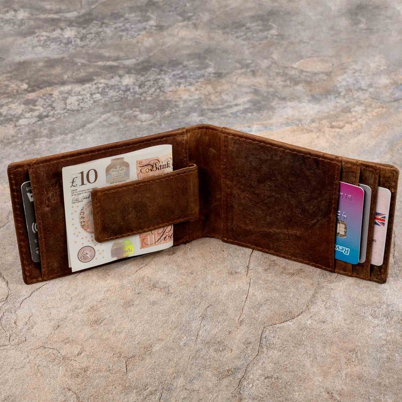 May include: A brown leather wallet with a money clip and multiple card slots. The wallet is open and has a ten pound note inside.
