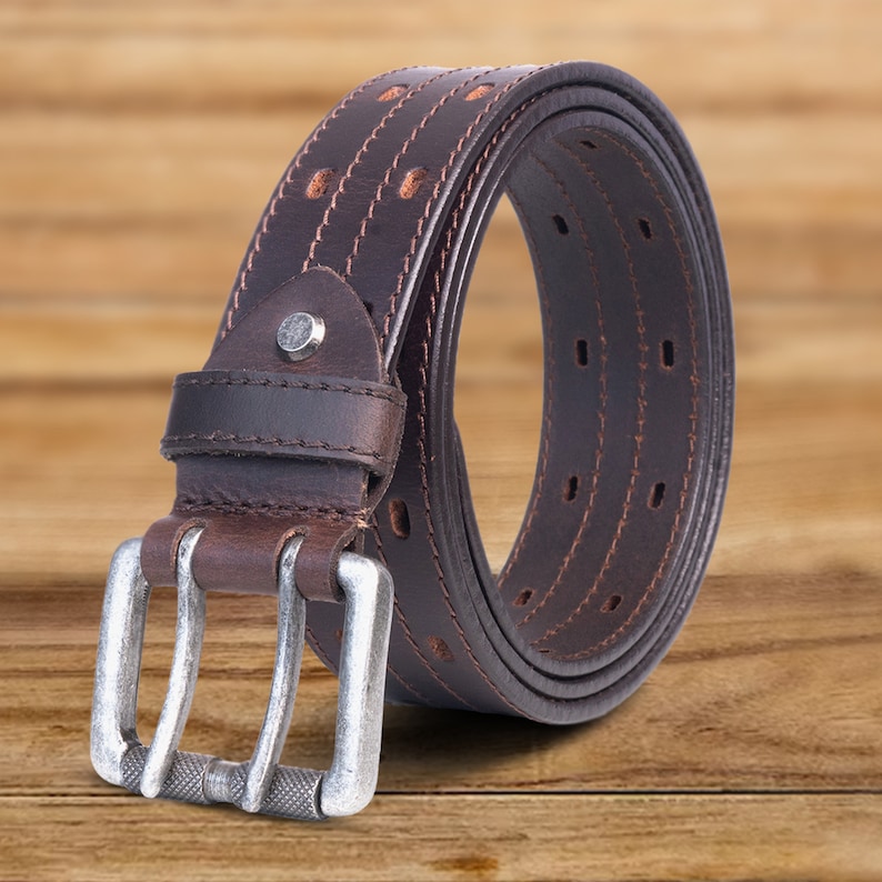 May include: A brown leather belt with a silver buckle. The belt has a double layer design with stitching and holes for adjusting the size.