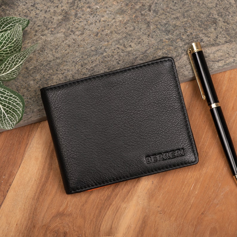May include: Black leather wallet with a stitched edge and the word "BERRERI" embossed in gold lettering.