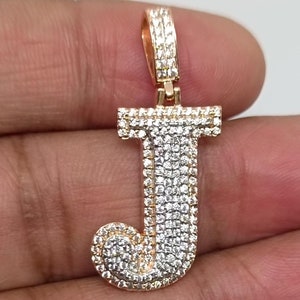 May include: A gold pendant in the shape of the letter J, encrusted with small, clear diamonds.