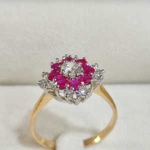 May include: A gold ring featuring a cluster of red rubies and white diamonds set in a white metal setting.