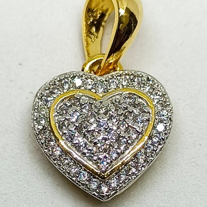 以下が含まれることがあります： キラキラと輝く透明な石で覆われた、小さなハートが内側に埋め込まれた、金のハート型のペンダント
