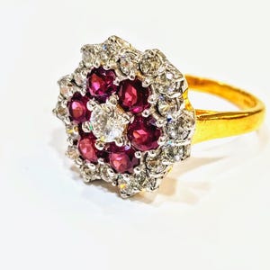 May include: A gold ring featuring a cluster of red rubies and white diamonds set in a flower design.