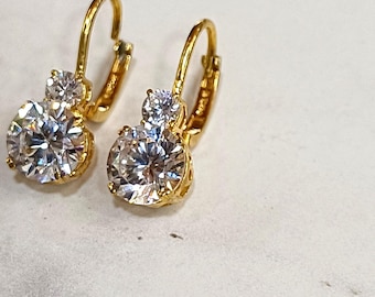 May include: A pair of gold hoop earrings with two clear round cubic zirconia stones on each earring.