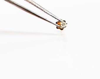 May include: A small, gold-colored flower-shaped stud earring with a clear, sparkly center stone.