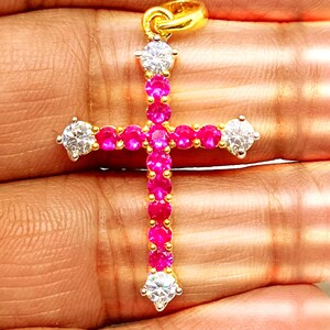 May include: A gold cross pendant with a red ruby and white diamond accents.