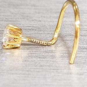 Peut inclure: Un anneau de nez en or avec une pierre ronde transparente.