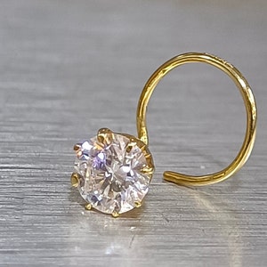 Peut inclure: Un anneau de nez en or avec une grosse pierre ronde transparente.