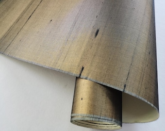 May include: A roll of metallic gold fabric with a subtle striped pattern. The fabric has a sheen and a slightly textured surface.