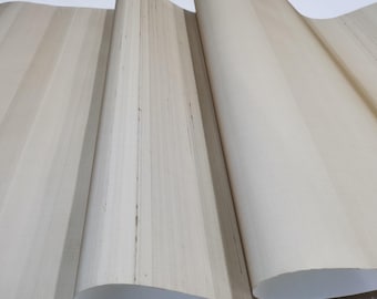May include: A close-up of a beige wallpaper with a subtle vertical striped pattern. The wallpaper is rolled up and the texture is visible.
