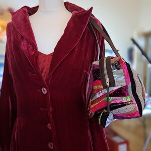 K&ouml;nnte beinhalten: Ein roter Samtblazer mit einreihigem Verschluss und eine bunte Patchwork-Handtasche mit braunem Riemen.