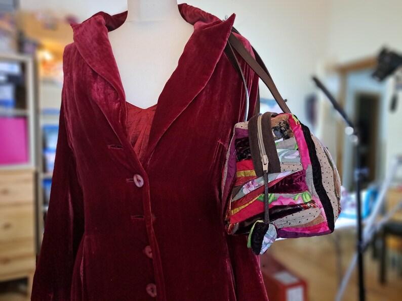 K&ouml;nnte beinhalten: Ein roter Samtblazer mit einreihigem Verschluss und eine bunte Patchwork-Handtasche mit braunem Riemen.