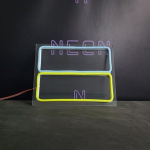 May include: A neon sign with the word "NEON" in purple, blue, and yellow. The sign is on a black background.