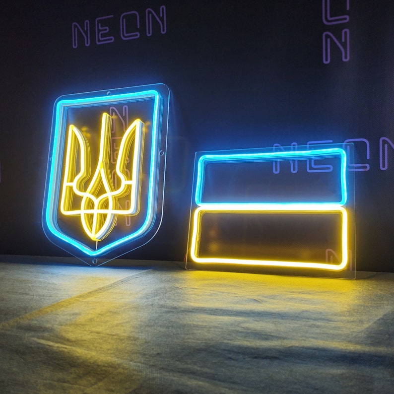 May include: Two neon signs, one depicting the Ukrainian coat of arms in yellow and blue, and the other a simple yellow and blue rectangle. Both signs are illuminated and have a clear plastic backing.