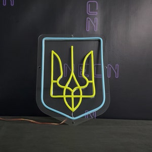 May include: A neon sign depicting the Ukrainian coat of arms, a yellow trident, inside a blue outline. The sign is mounted on a clear acrylic backing.