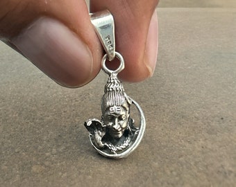 May include: Silver pendant featuring a detailed depiction of the Hindu deity Shiva, with a snake and crescent moon design.
