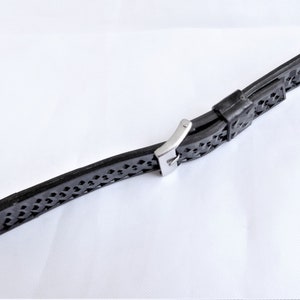 Puede incluir: Una correa de reloj de caucho negro con una hebilla de acero inoxidable. La correa tiene un dise&ntilde;o estampado.