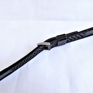 Puede incluir: Correa de reloj de goma negra con hebilla plateada.