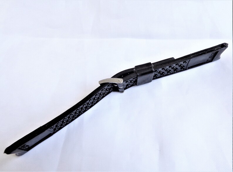 Puede incluir: Correa de reloj de goma negra con hebilla plateada.