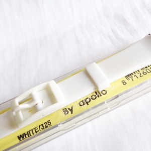 Könnte beinhalten: Weißes Uhrenarmband mit einer Schließe und dem Text "WHITE/325 by apollo" und dem Barcode 8 7126010630 auf einem gelben Etikett.
