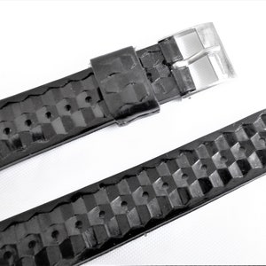 Puede incluir: Correa de reloj de cuero negro con un patr&oacute;n a cuadros y una hebilla plateada.