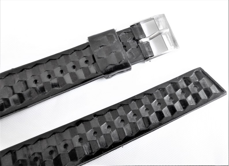 Puede incluir: Correa de reloj de cuero negro con un patr&oacute;n a cuadros y una hebilla plateada.