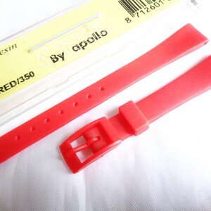 Könnte beinhalten: Rotes Armband aus Harz mit einer Schnalle. Das Armband ist mit "RED/350" und "By Apollo" beschriftet.