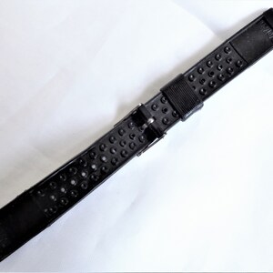 Puede incluir: Correa de reloj de goma negra con superficie texturizada y cierre de hebilla.