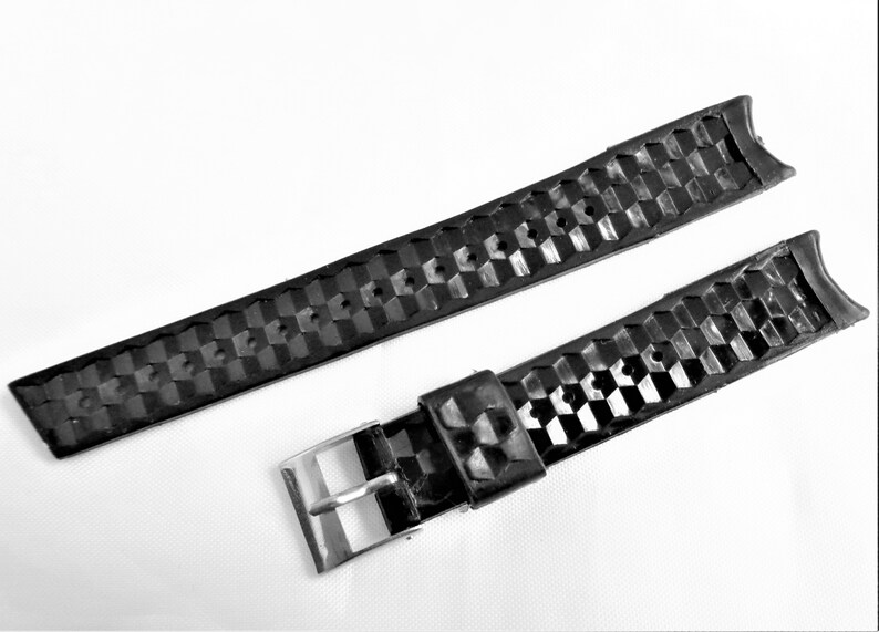 Puede incluir: Correa de reloj de caucho negro con un patr&oacute;n texturizado y una hebilla plateada.