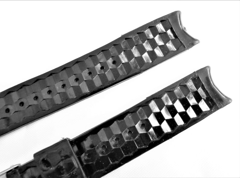 Puede incluir: Dos correas de reloj de goma negra con un patr&oacute;n texturizado a cuadros. Las correas tienen agujeros para ajustar el tama&ntilde;o.