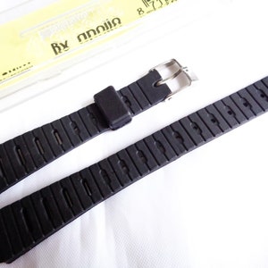 Könnte beinhalten: Schwarzes Kautschuk-Armband mit einer silbernen Schließe. Das Armband hat ein strukturiertes Design und ist kompatibel mit Uhren, die ein Standard-Armband von 18 mm verwenden.