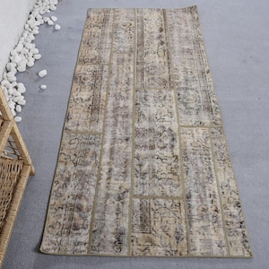 May include: A beige and brown patterned runner rug with a distressed look. The rug is made of recycled materials and has a unique patchwork design.