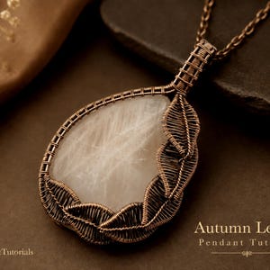 May include: A teardrop-shaped pendant featuring a smooth, translucent white stone encased in intricate, dark copper wire wrapping. The wire design forms a series of leaf-like shapes along the edge. The text Autumn Leaves Pendant Tutorial is visible.
