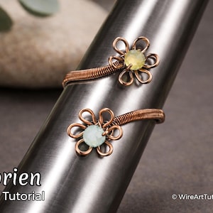 May include: Two copper wire rings with flower designs, each featuring a central gemstone. One ring has a yellow gemstone, the other a light blue gemstone. The rings are displayed on a silver metal cone. Text reads "Florien Ring Tutorial".