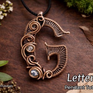 May include: Copper-colored wire-wrapped pendant in the shape of the letter "G", adorned with clear gemstones. The pendant hangs from a black cord. The text "Letter G Pendant Tutorial" is visible in the image.