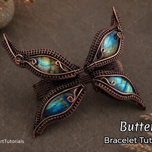 May include: A copper-toned wire-wrapped butterfly bracelet featuring four iridescent blue and green gemstones. The bracelet, crafted with intricate wirework, is displayed on a dark surface. The image includes the text "Butterfly Bracelet Tutorial".