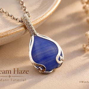 Puede incluir: Un colgante de piedra azul en forma de lágrima envuelto en alambre de color plateado, suspendido de una cadena de metal a juego. El texto Dream Haze Pendant Tutorial y WireArtTutorials es visible en la imagen, con un acabado liso y pulido.