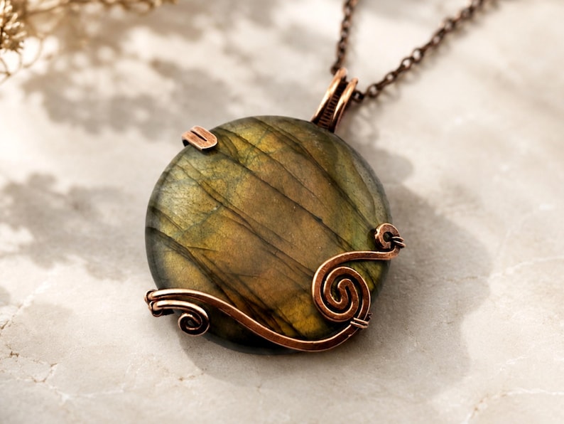 May include: A round labradorite pendant featuring a dark green and gold iridescent surface, encased in a decorative copper wire wrap with spiral accents. The pendant hangs from a dark copper-toned metal chain, showcasing a polished finish.