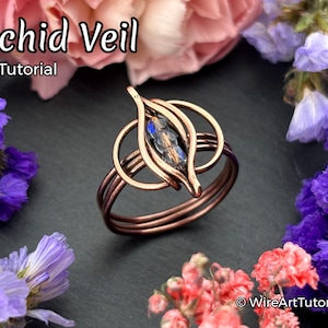 May include: Copper-colored ring with an orchid-inspired design, featuring a central leaf-shaped element holding blue and clear beads. The ring is surrounded by floral arrangements, with the text "Orchid Veil Ring Tutorial".