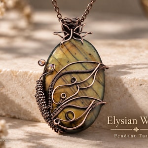 May include: An oval labradorite pendant wrapped in dark copper wire with intricate swirling patterns and small crystal accents. The pendant hangs from a matching copper chain and features the text Elysian Wings Pendant Tutorial.