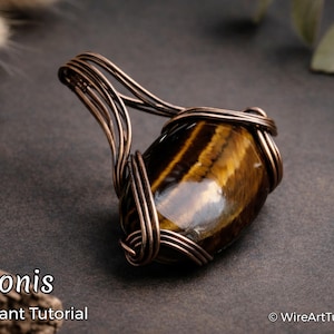 May include: A handcrafted pendant featuring a polished tiger's eye gemstone wrapped in copper wire. The pendant has a warm, golden-brown color with dark brown stripes. The image includes the text "Amonis Pendant Tutorial".