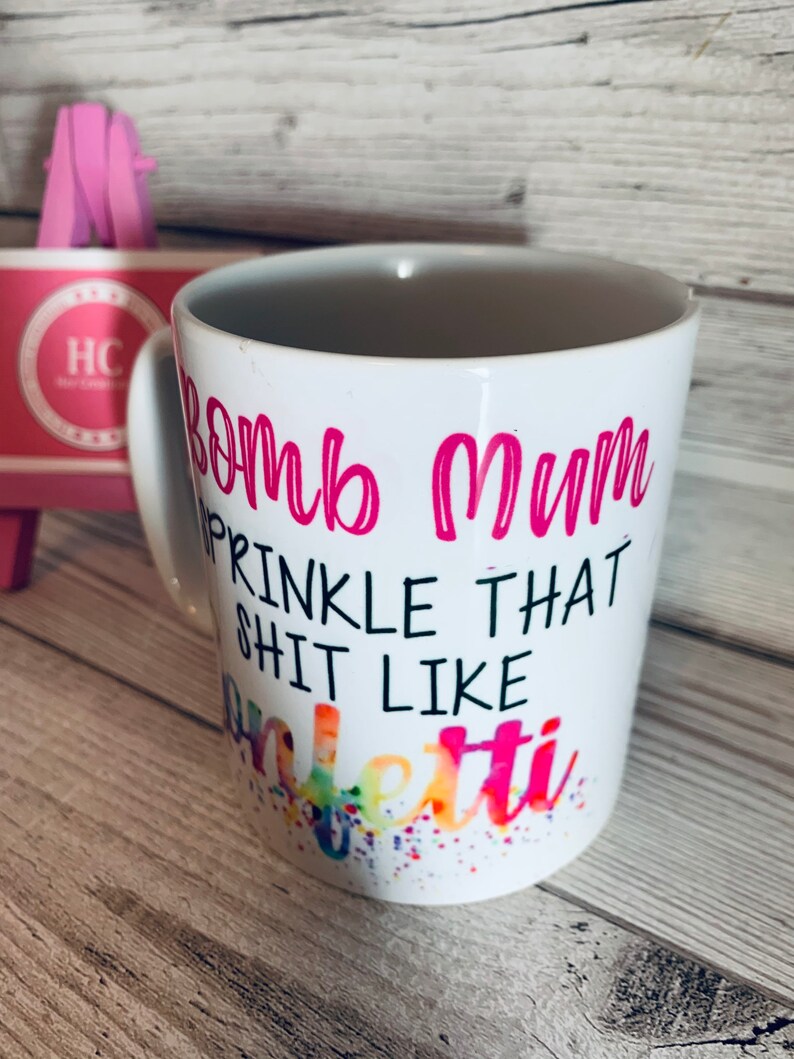 May include: White ceramic mug with a pink design that says "Bomb Mum Sprinkle That Shit Like Confetti".