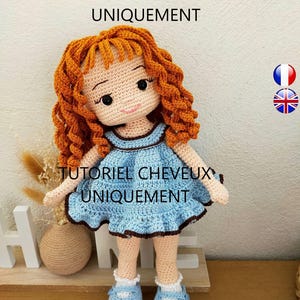 May include: A crocheted doll with curly orange hair wearing a light blue dress with brown trim and matching light blue shoes. The text TUTORIEL CHEVEUX LONGS UNIQUEMENT and TUTORIEL CHEVEUX UNIQUEMENT is visible on the image along with flag icons.