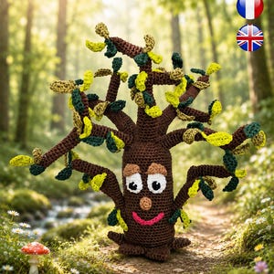 Peut inclure: Une figurine d'arbre crochetée en marron avec un tronc cylindrique, un visage souriant et de grands yeux blancs. L'arbre présente de multiples branches ornées de petites feuilles texturées dans des tons vert lime, vert foncé et jaune.