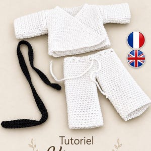 May include: A white crocheted kimono-style top and matching trousers set with a long black crocheted belt. The set features a wrap-front design on the top and a drawstring waist on the trousers. The text "Tutoriel Kimono" is printed at the bottom.
