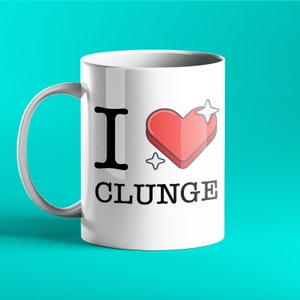 May include: White ceramic coffee mug with a black and red design. The mug has the text "I love Clunge" and a red heart with a sparkle above it.